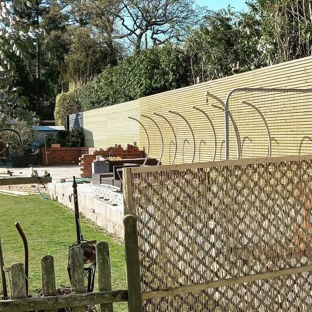 Timber fence panel with trellis topper against a garden border