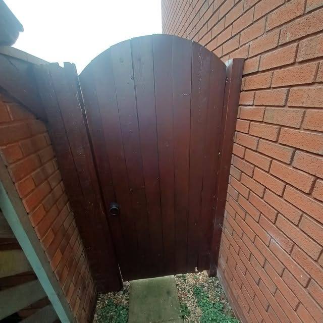 Timber side gate fitted next to a brick wall